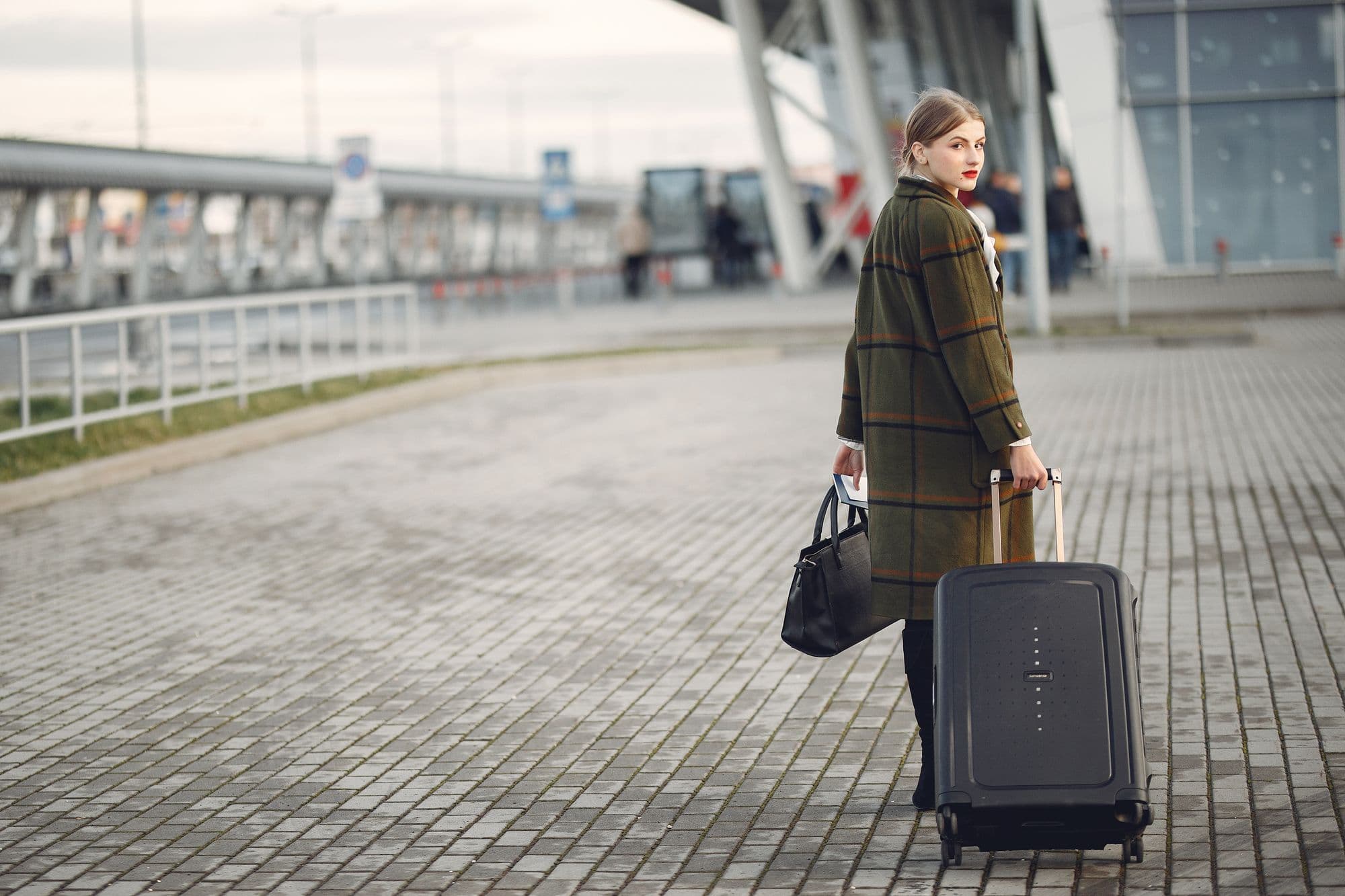 Une voyageuse et sa valise à la sortie d’un terminal